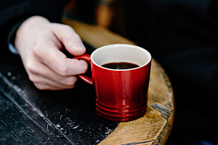 Mão segurando caneca vermelha 200ml com Café