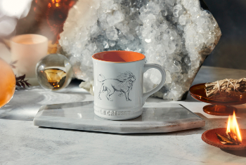 white mug with orange interior and a lion design on side