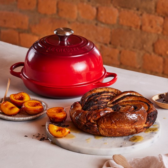 flame orange cast iron bread oven in front of loaves of fresh baked bread