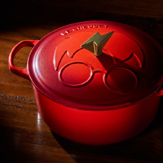 red dutch oven with a simple illustration of Harry Potter embossed on the lid and a gold lightning bolt knob