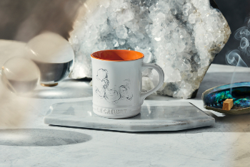 white mug with orange interior and an aquarius design on side
