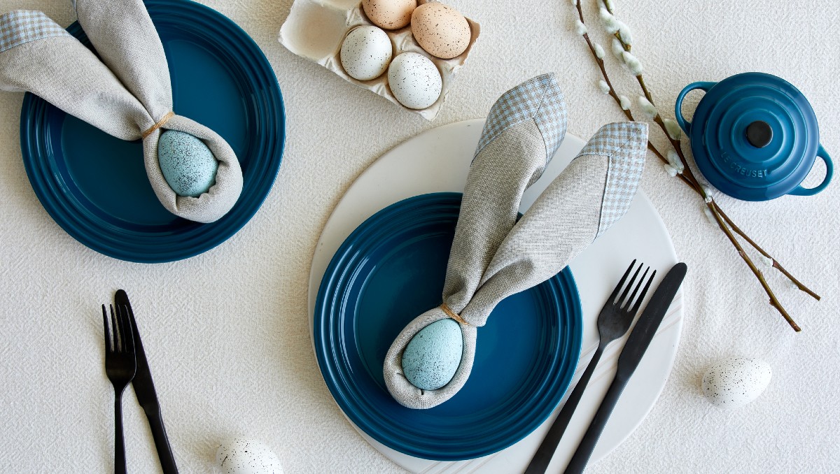 tablescape of Le Creuset dinnerware, lit candles and rustic fall accents