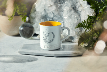 white mug with yellow interior and a virgo design on side